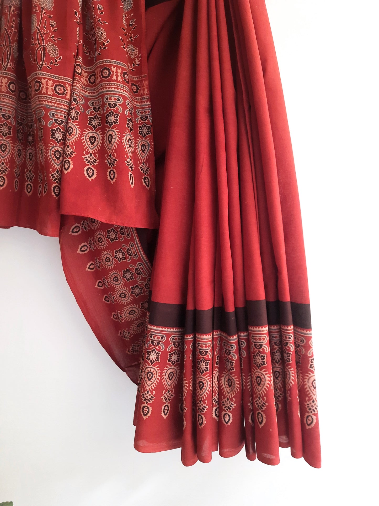 Ajrakh hand block print pure cotton saree dyed in vibrant madder hues, showcasing intricate traditional patterns.