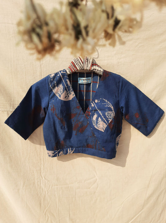 Indigo is brought to life through ecoprinting in this unique blouse. Expertly crafted using the traditional ajrakh technique, it features a V-neck front, high round neck back, and side zip. Lined with our hand block print ajrakh checkered fabric, you'll fall in love with the intricate details and sustainable process behind this piece.