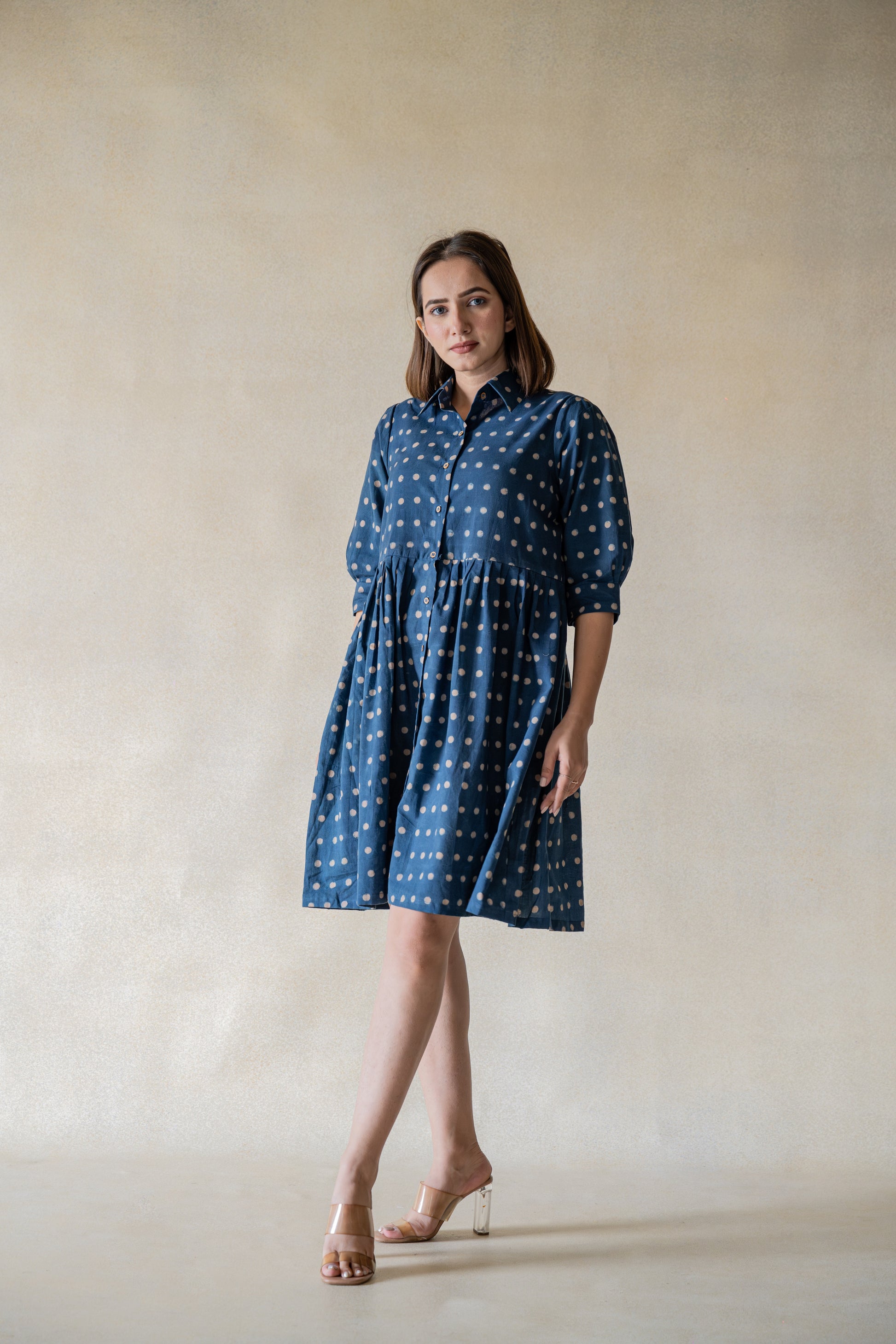 Crafted from sustainable material, the Indigo Dazzle Polka Shirt Dress is a must-have for any fashion-forward individual. The dress boasts an indigo dye and ajrakh hand block printed polka dots for a chic and unique look. With gathered and pleated sleeves, this dress offers a comfortable and flowy fit that will elevate your wardrobe.