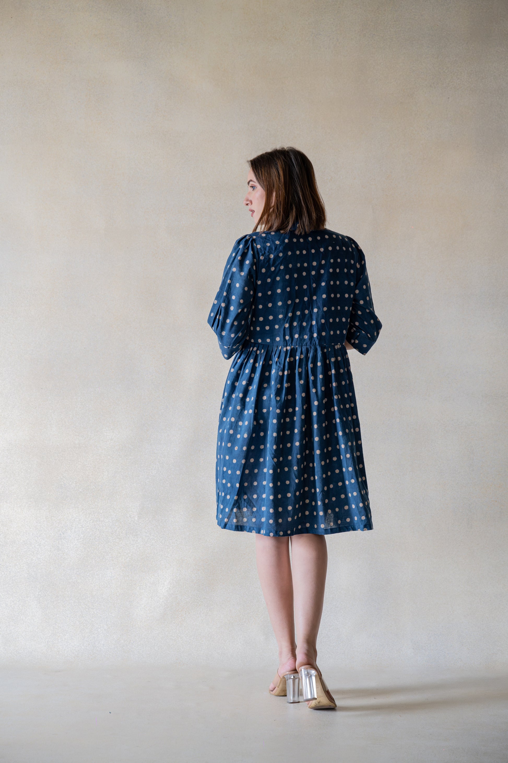Crafted from sustainable material, the Indigo Dazzle Polka Shirt Dress is a must-have for any fashion-forward individual. The dress boasts an indigo dye and ajrakh hand block printed polka dots for a chic and unique look. With gathered and pleated sleeves, this dress offers a comfortable and flowy fit that will elevate your wardrobe.