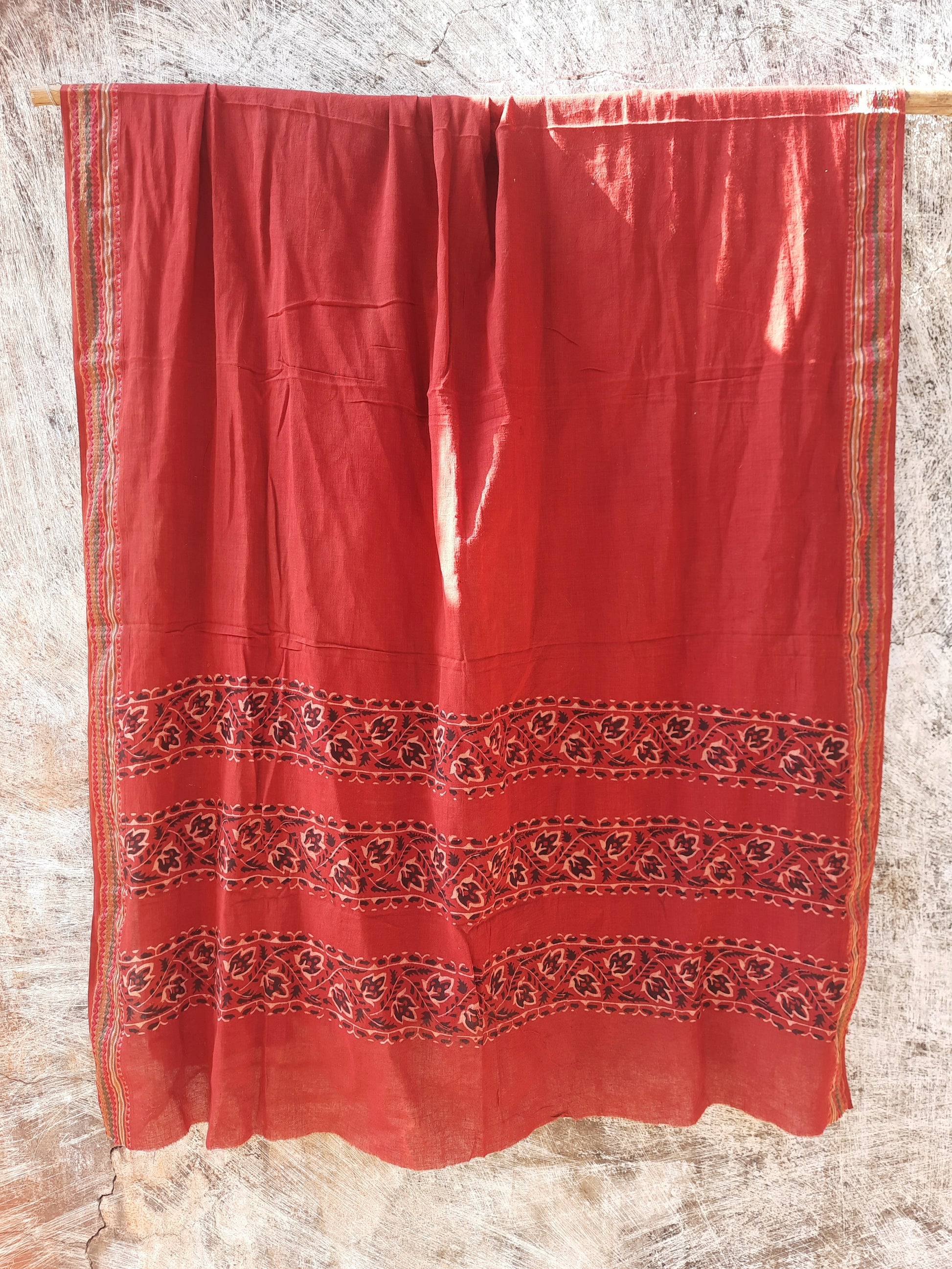 Madder-dyed pure cotton dupatta featuring intricate Ajrakh hand block printed borders. Crafted mindfully and naturally dyed, this lightweight and breathable dupatta adds a touch of Indian tradition to any outfit. Perfect for festive or everyday wear.