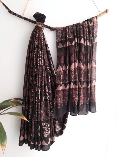 Charcoal Black Ajrakh Saree, combining artisanal expertise with natural dyes and hand block printing. Made from pure cotton, it offers both style and comfort. Slow made and conscious, it's a tasteful addition to your collection. Includes a running blouse for a complete, luxurious look.