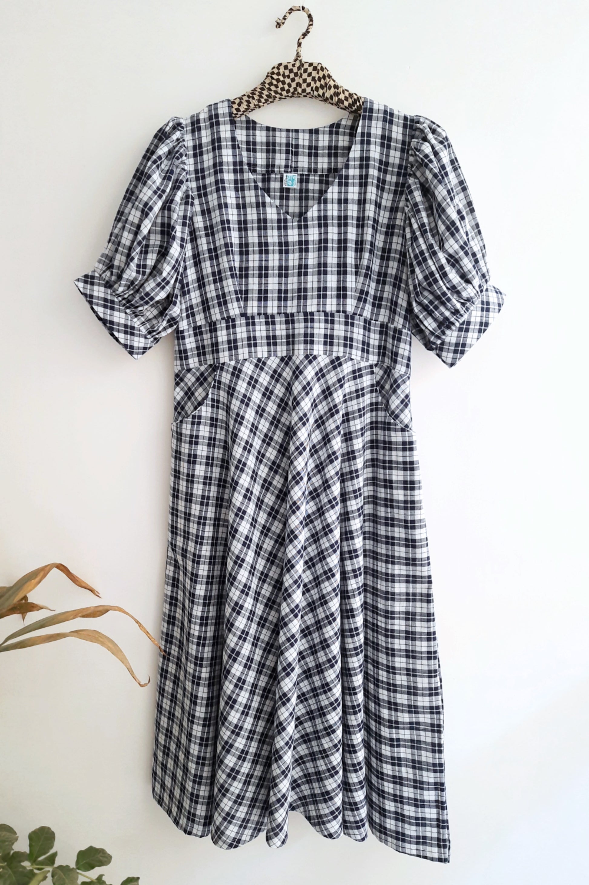 Checkered Dress in Blue & White color for women with V-neck, puffy sleeves, and front pockets, made from sustainable cotton.
