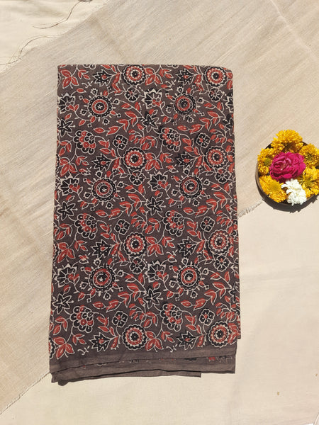 Earthy brown Ajrakh hand block printed fabric in pure cotton, crafted using natural dyes. Featuring intricate floral motifs, eco-friendly, breathable, and artisan-made. Traditional Indian textile, slow-made and consciously crafted. Width: 44 inches.