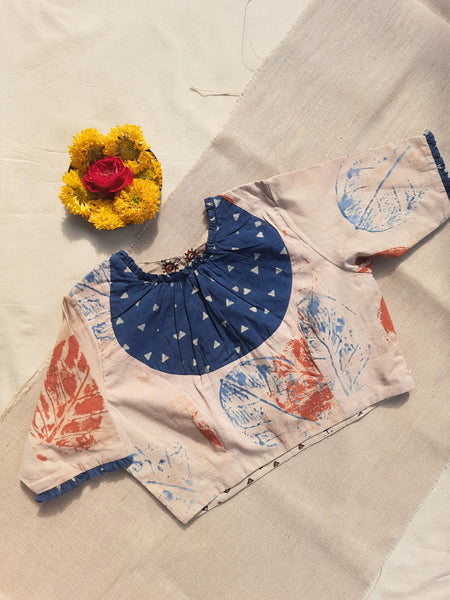 Earthy peach eco-printed cotton blouse with indigo Ajrakh patch on the neck, frill accents on sleeves and neckline, side zip closure, and a peep-hole button back. Lined with pure cotton Ajrakh fabric, naturally dyed, handcrafted, and includes 2-inch extra margins inside.