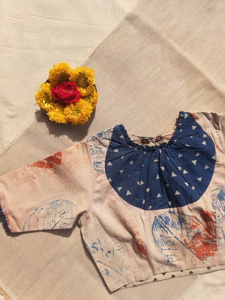 Earthy peach eco-printed cotton blouse with indigo Ajrakh patch on the neck, frill accents on sleeves and neckline, side zip closure, and a peep-hole button back. Lined with pure cotton Ajrakh fabric, naturally dyed, handcrafted, and includes 2-inch extra margins inside.