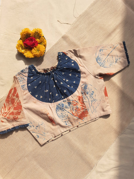 Earthy peach eco-printed cotton blouse with indigo Ajrakh patch on the neck, frill accents on sleeves and neckline, side zip closure, and a peep-hole button back. Lined with pure cotton Ajrakh fabric, naturally dyed, handcrafted, and includes 2-inch extra margins inside.