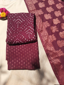 Handcrafted wine Rai Bandhani cotton suit set featuring traditional tie-dye patterns. The set includes a soft cotton top, a Jacquard cotton bottom, and a dupatta adorned with intricate zari motifs. Ethnic Indian wear, crafted by skilled artisans in Jetpur, Gujarat. Perfect for festive occasions, weddings, and cultural celebrations. A timeless blend of heritage craftsmanship and contemporary elegance.