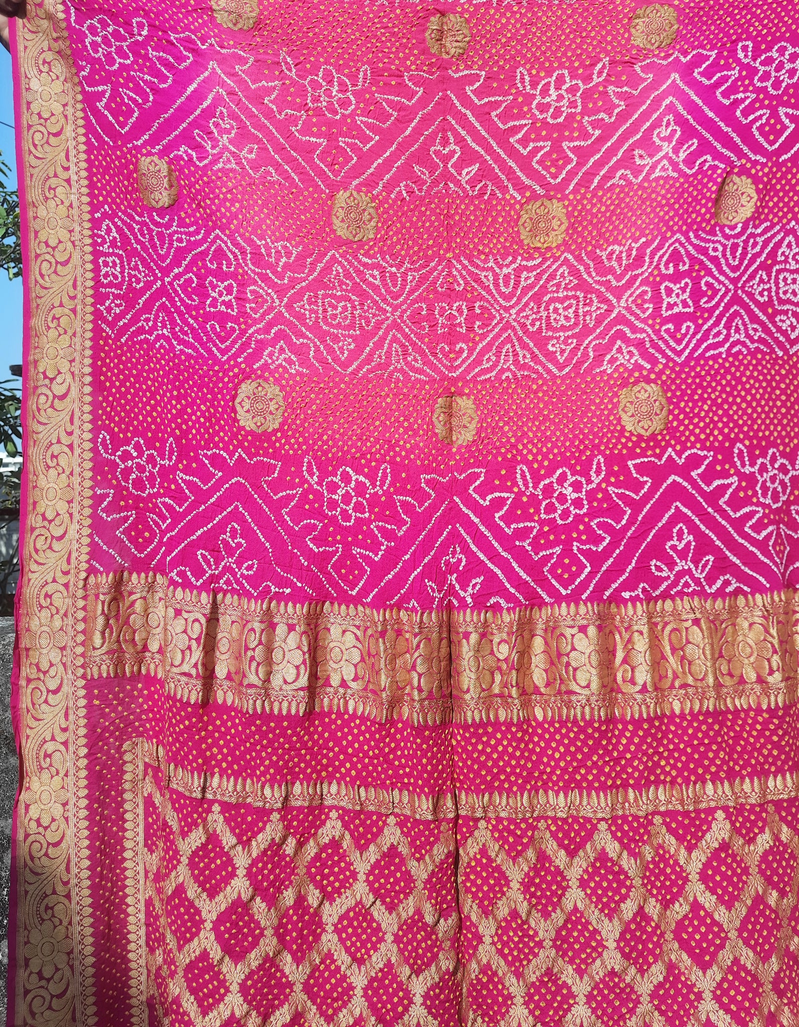 Handcrafted Rai Dani Bandhani saree in pure georgette, rani pink shade with intricate kadwa zari borders and motifs, includes matching Bandhani blouse. Ethically made, luxurious drape, perfect for festive and traditional occasions. Exclusively at Turquoisethestore.