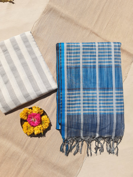 Handwoven shades of blue cotton saree, lightweight and breathable. Ethically crafted with a soft drape, paired with a hand-spun organic cotton blouse piece in off-white and grey stripes. Perfect for effortless elegance and everyday comfort.