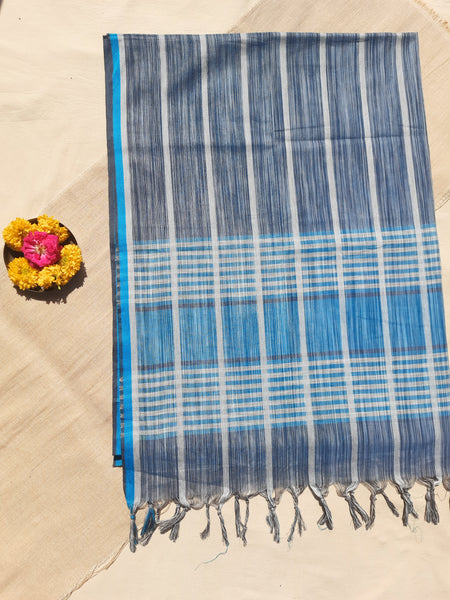 Handwoven shades of blue cotton saree, lightweight and breathable. Ethically crafted with a soft drape, paired with a hand-spun organic cotton blouse piece in off-white and grey stripes. Perfect for effortless elegance and everyday comfort.