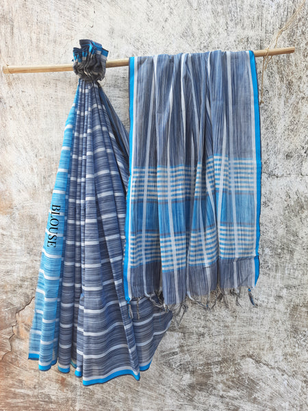 Handwoven shades of blue cotton saree, lightweight and breathable. Ethically crafted with a soft drape, paired with a hand-spun organic cotton blouse piece in off-white and grey stripes. Perfect for effortless elegance and everyday comfort.