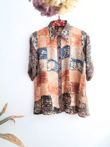 A woman wearing Earth's Palette Luxurious Modal Silk Shirt, featuring a unique abstract print in peach, indigo, and black hues. This shirt exudes elegance and comfort, perfect for standing out with confidence all day long.