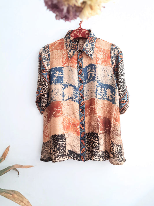 A woman wearing Earth's Palette Luxurious Modal Silk Shirt, featuring a unique abstract print in peach, indigo, and black hues. This shirt exudes elegance and comfort, perfect for standing out with confidence all day long.