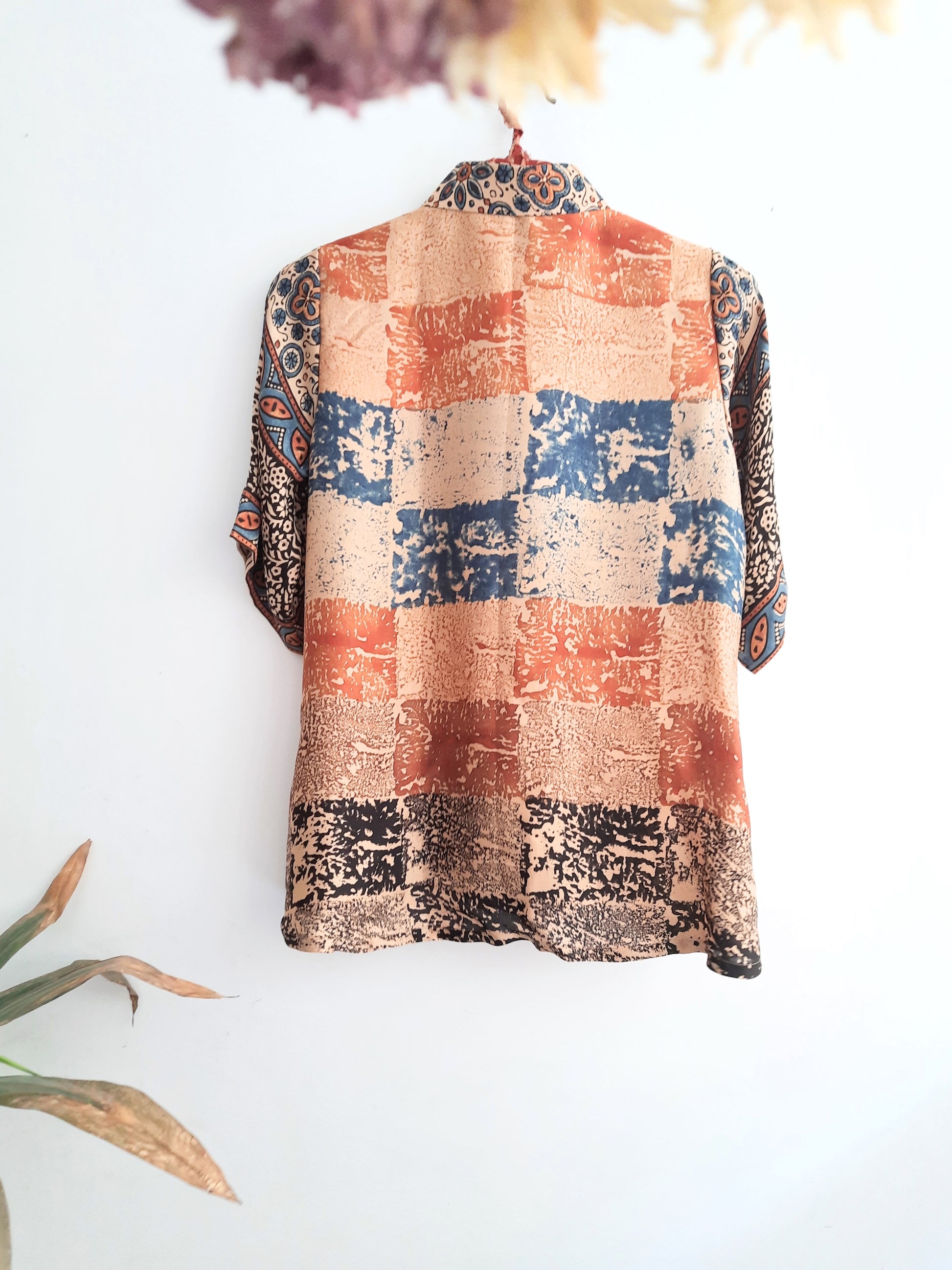 "Image: A woman wearing Earth's Palette Luxurious Modal Silk Shirt, featuring a unique abstract print in peach, indigo, and black hues. This shirt exudes elegance and comfort, perfect for standing out with confidence all day long."