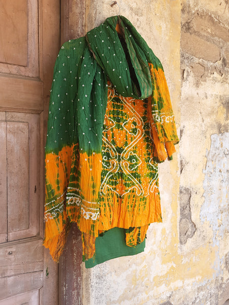 Handcrafted Shibori & Rai Dani Bandhani cotton suit set in yellow and green. Traditional Indian tie-dye dress material, artisan-made in Gujarat. Unstitched three-piece suit set, crafted consciously from pure cotton. Perfect for custom ethnic wear, salwar suits, or fusion outfits. A unique blend of heritage craftsmanship and sustainable fashion, showcasing intricate patterns and vibrant colors.